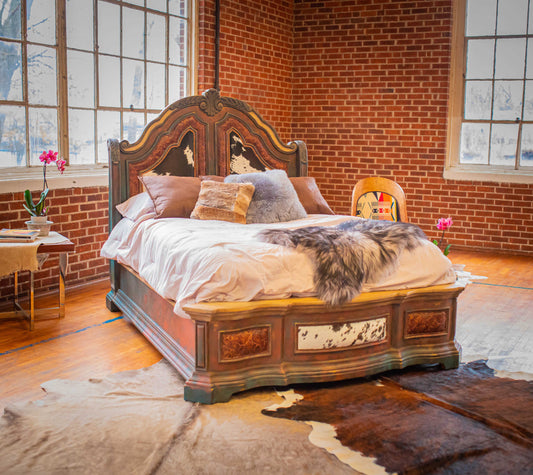 reclaimed piece that has been reconditioned with the addition of hand painting in rich, warm, earthy colors and embellished with tooled leather, cowhide and copper tacking, queen bed, with sheep skin and cowhide decor